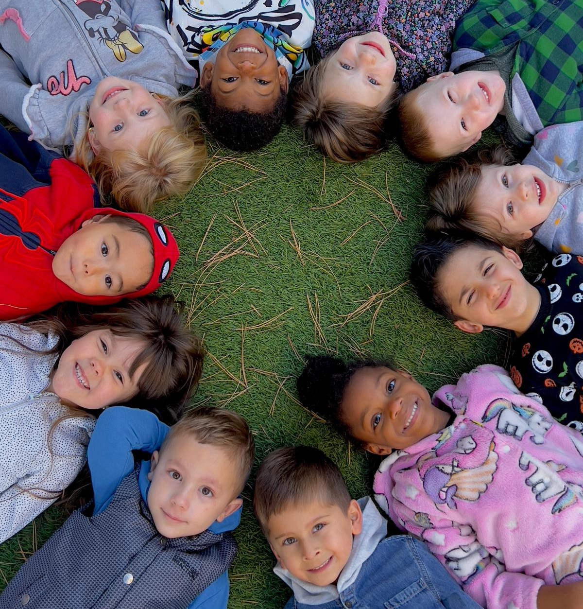 Happy children laying down in a circle at Little Geniuses Learning Center
